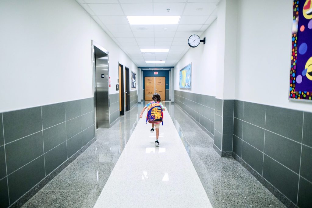 Kuvituskuva lapsesta juoksemassa koulun käytävällä.
