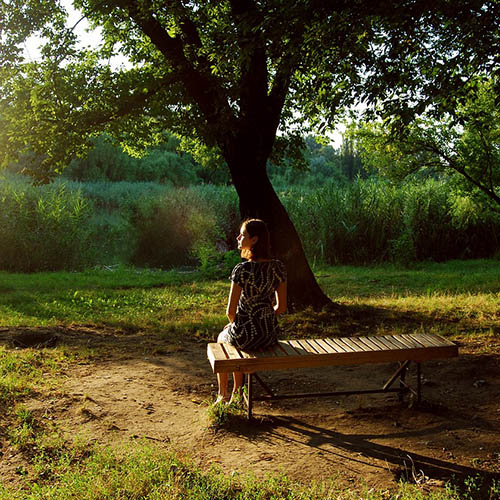 Adoptio-odotusta; nainen istuu penkillä keskellä vehreää luontoa ja odottaa.